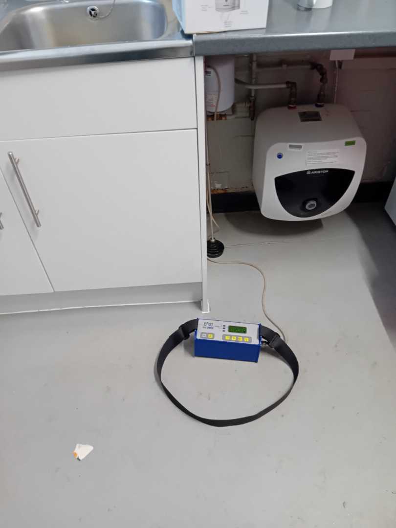 Tracer-gas analyser in front of an open sink cupboard